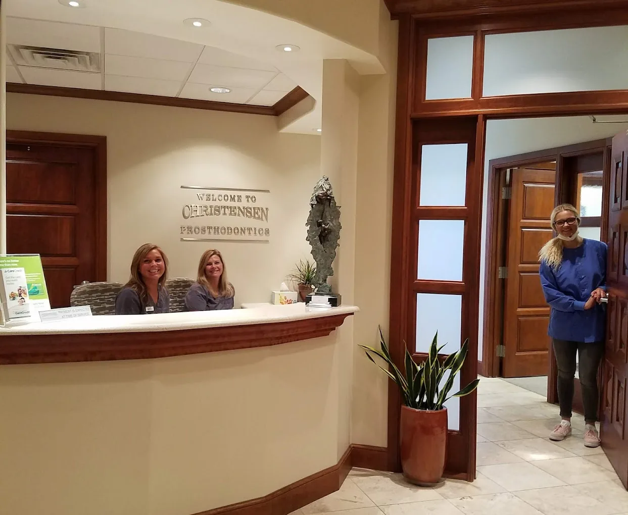 Front desk at Christensen Prosthodontics in Orem with the Welcome to Christensen Prosthodontics sign and two team members