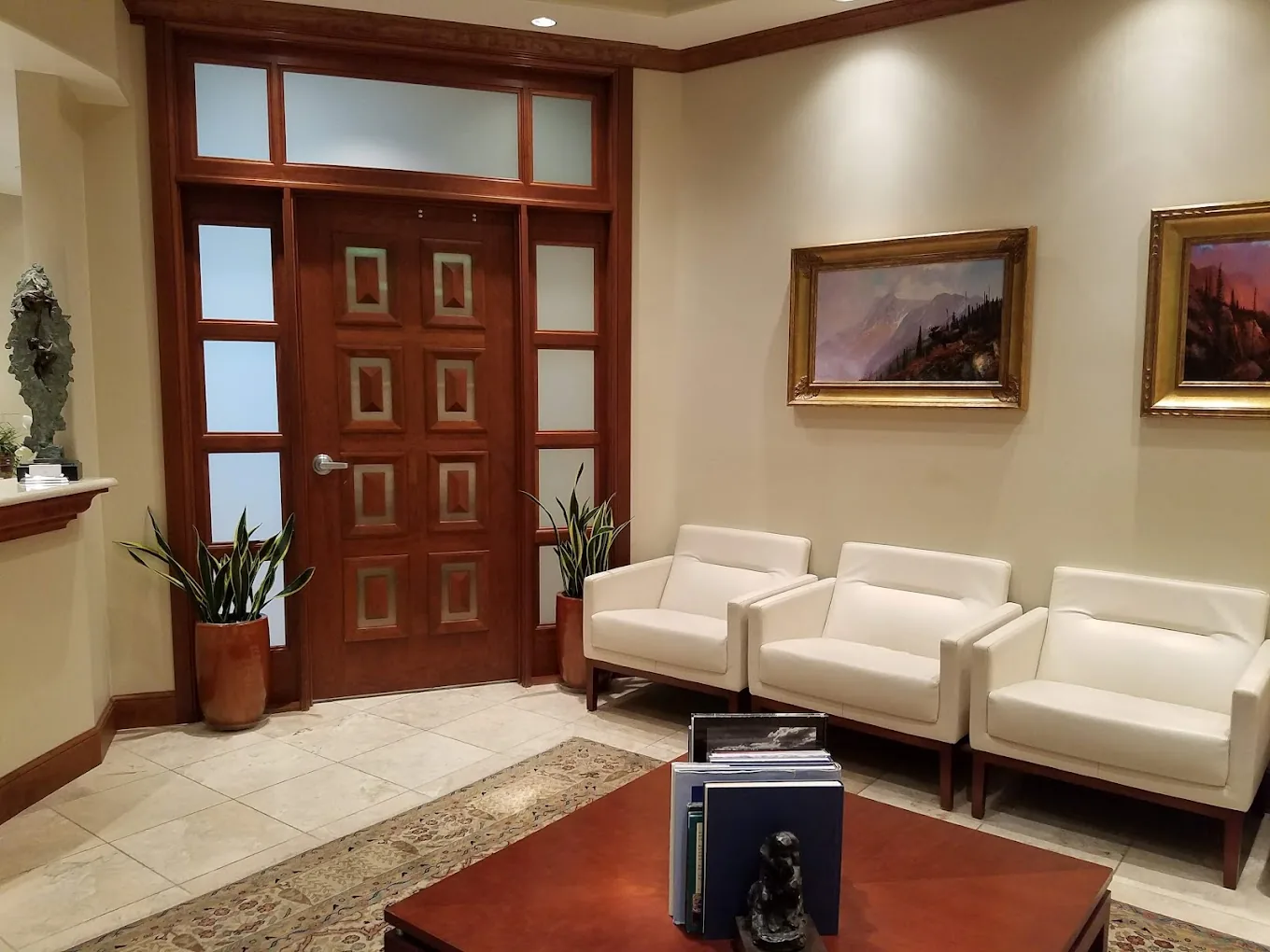 Waiting room at Christensen Prosthodontics with white armchairs and mountain landscape paintings